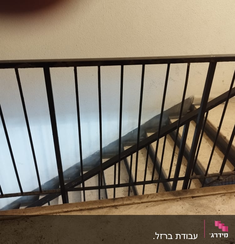 מעקה מתכת שחור על מדרגות בטון